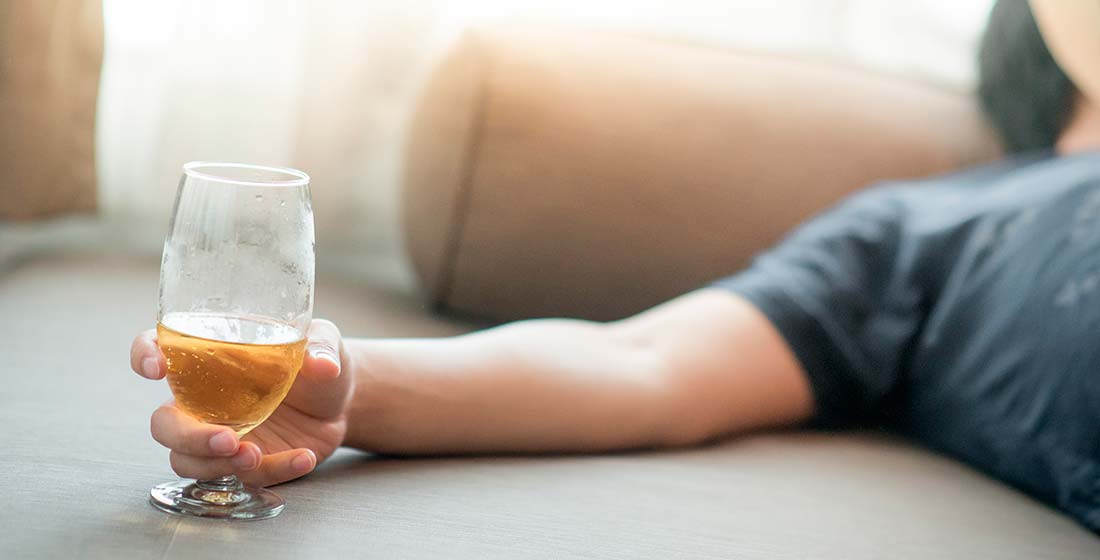 мужчина спит на диване со стаканом алкоголя в руке